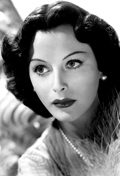 A publicity photo of Hedy Lamarr looking off camera. She has dark hair and wears bold makeup.